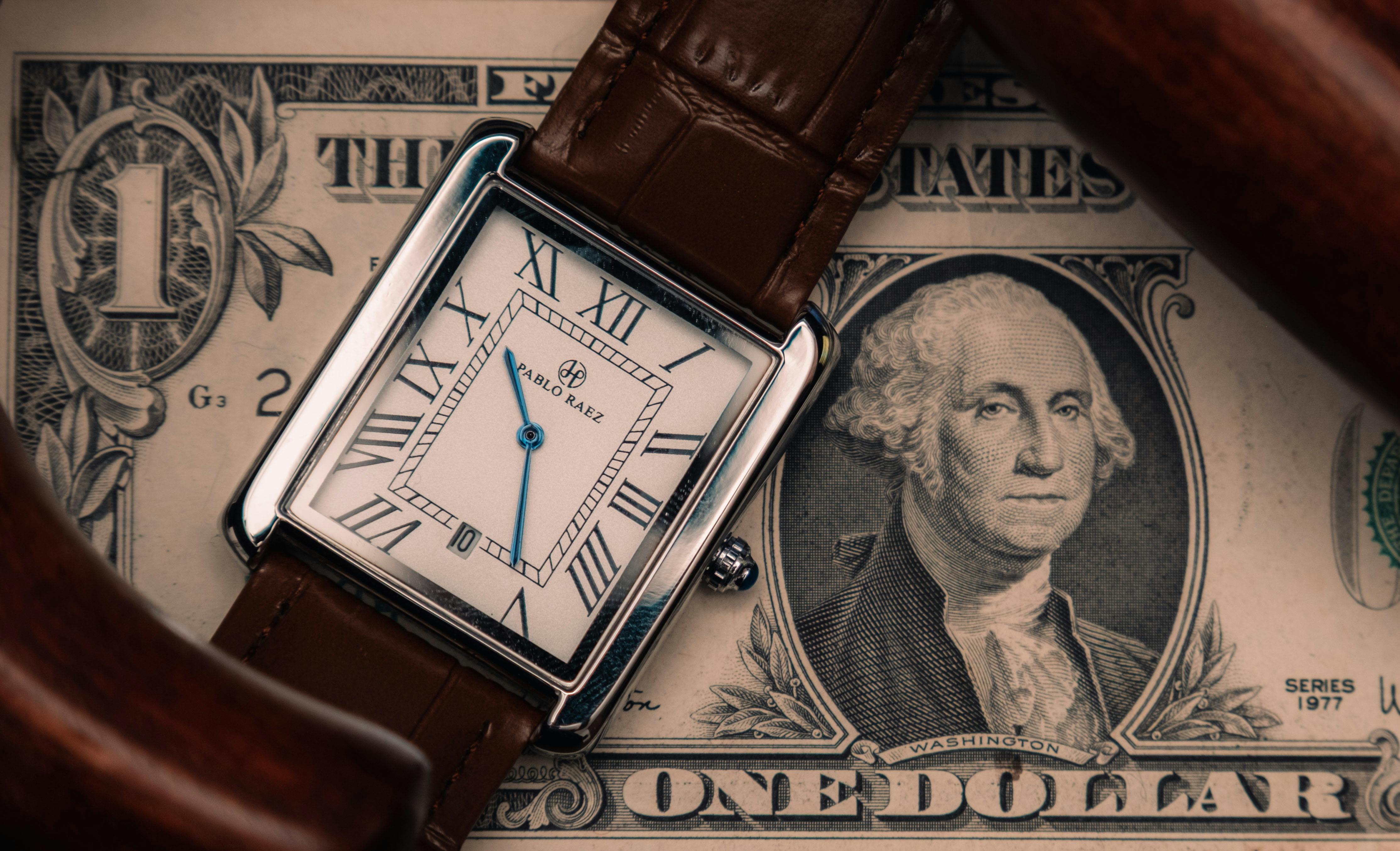 Reloj de lujo sobre billete para ilustrar precio y valor